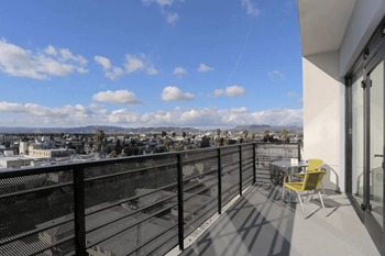 a balcony with a table and chairs and a view of the city